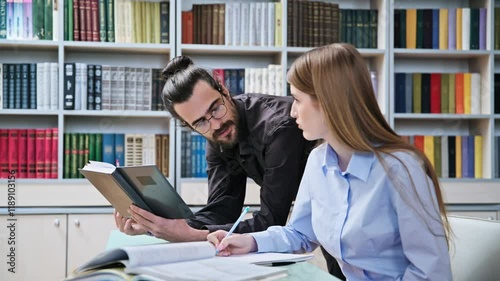 Teenage student girl studying with male teacher inside classroom library