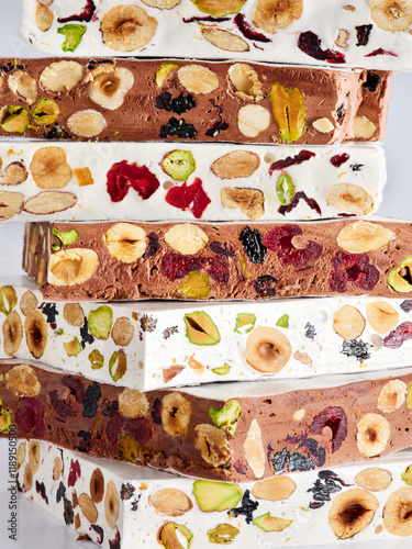 Different layers of nougat stacked together highlight a variety of nuts and dried fruit. The colorful textures and contrasts create an appealing visual. Perfect for festive occasions photo