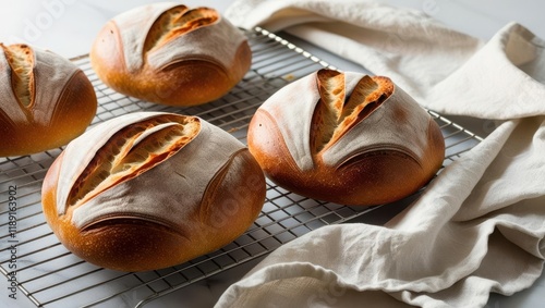 Freshly baked bread rolls cooling on a wire rack, showcasing a golden crust and unique scoring patterns, paired with a soft linen cloth.