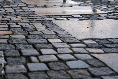 A closeup of a cobblestone street with uneven stones after rain photo