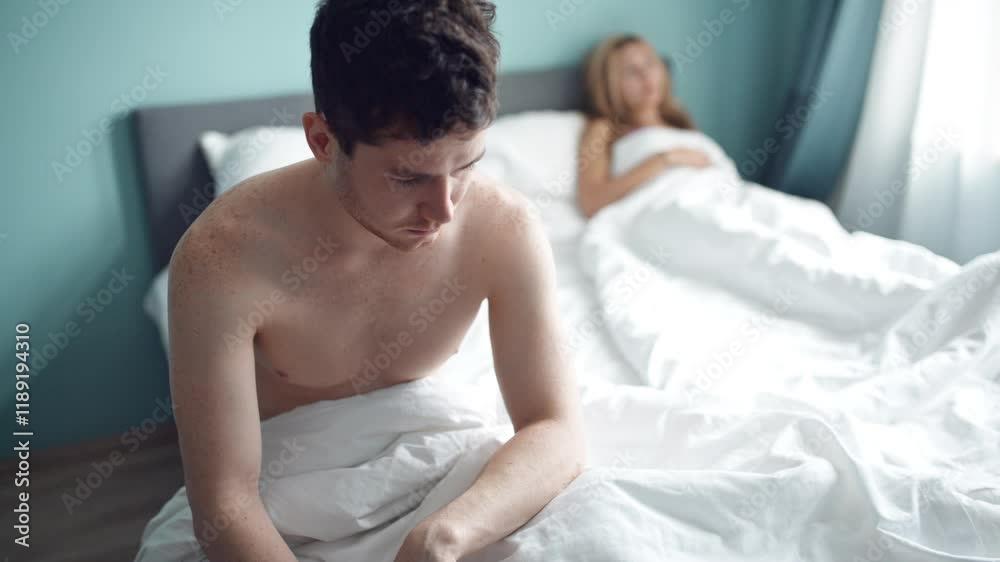 Frustrated man sitting on bed on different side of woman. Young unhappy couple having problem in bedroom, quarrel between lovers. Divorce, marriage, conflict, family crisis, love concept.
