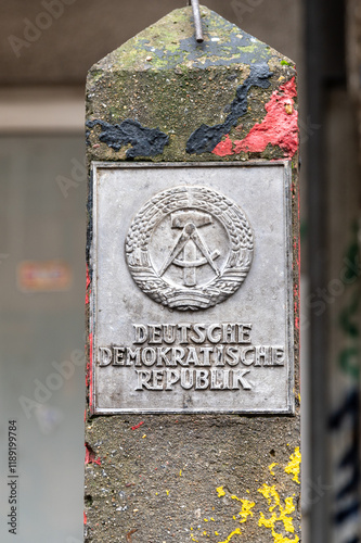 Metal plaque with the East German flag on mounted on a concrete post
