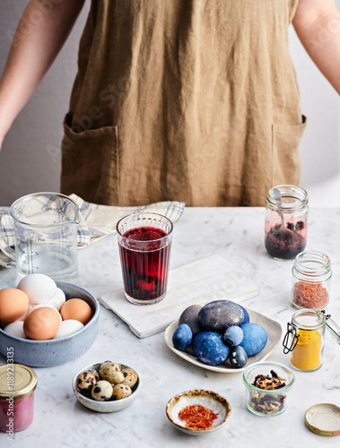 A glass with a staining solution and an egg in it and already stained blue eggs photo