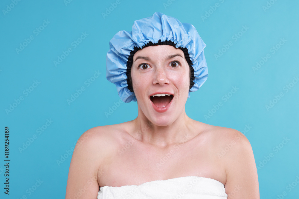 Emotional woman in shower cap on light blue background Emotional woman in shower cap on light blue background
