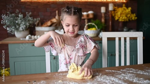 Little girl playing with dough on wooden table