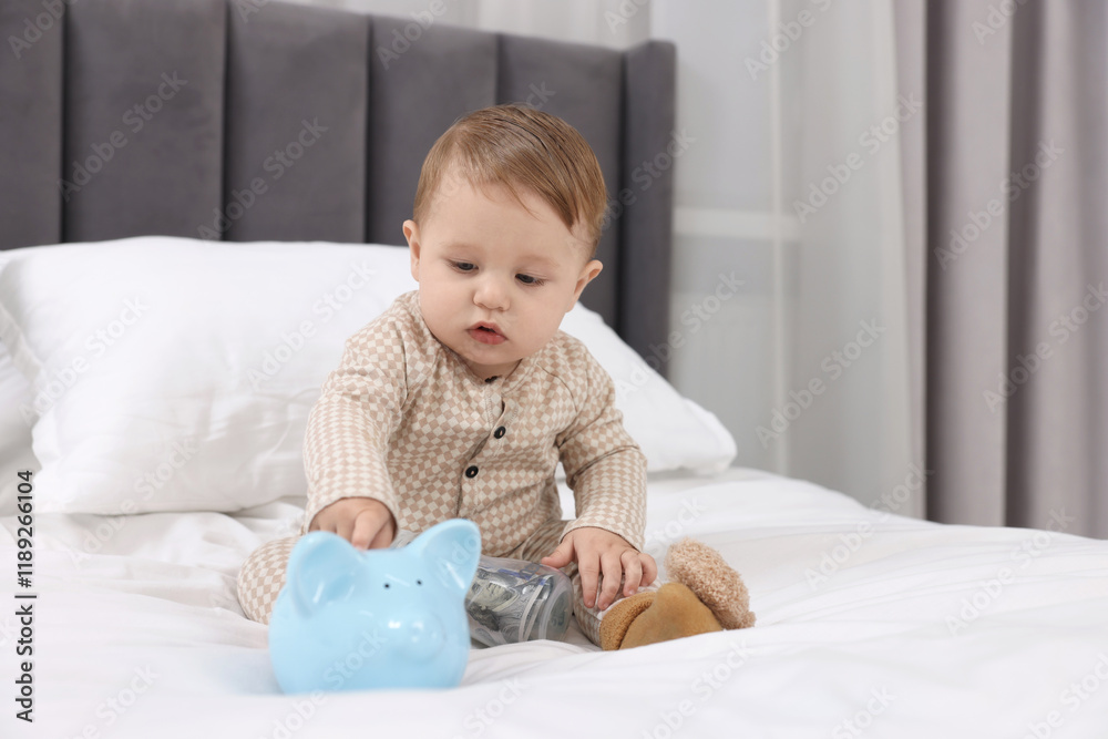Cute little baby with piggybank on bed at home Cute little baby with piggybank on bed at home