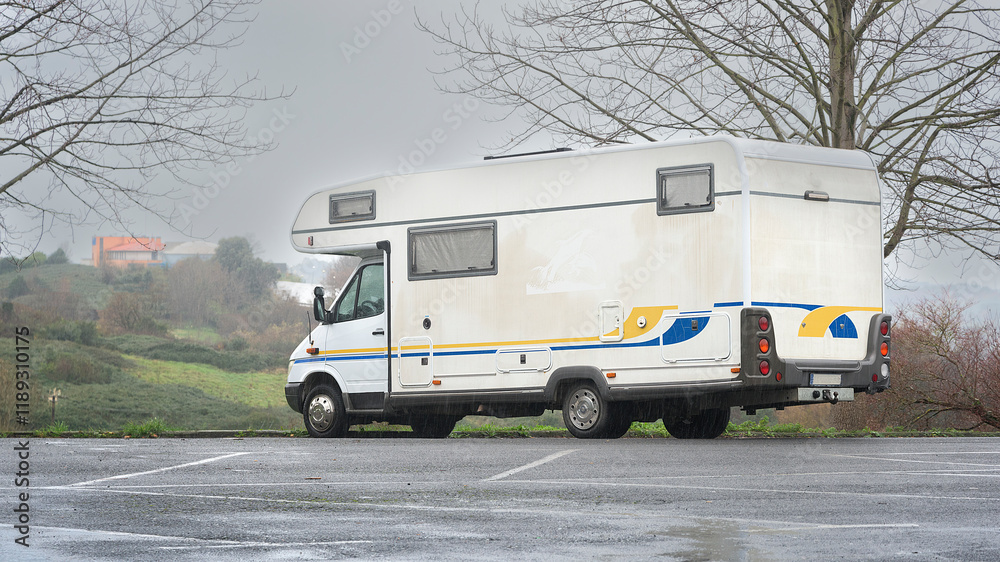 Naklejka premium Motorhome parked in a parking lot in Akarlanda, Bizkaia, on a rainy morning. Winter tourism concept