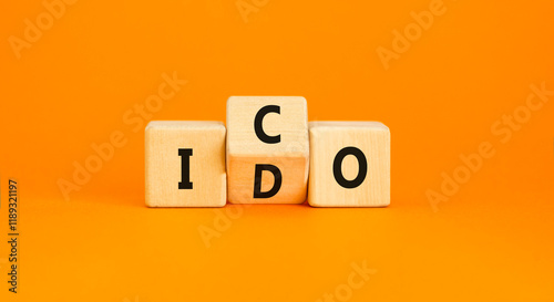 Initial coin or DEX offering symbol. Concept words abbreviation ICO or IDO on wooden block. Beautiful orange table orange background. Business Initial coin or DEX offering concept. Copy space. photo