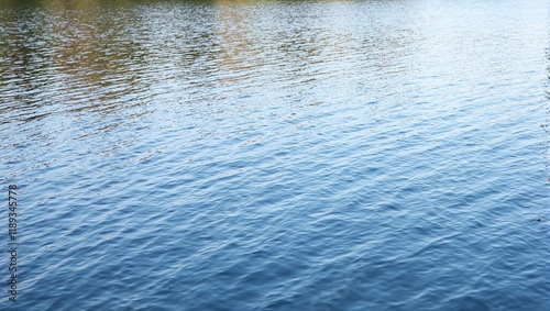 Abstract rippled water surface with sky and tree reflections creating a tranquil texture