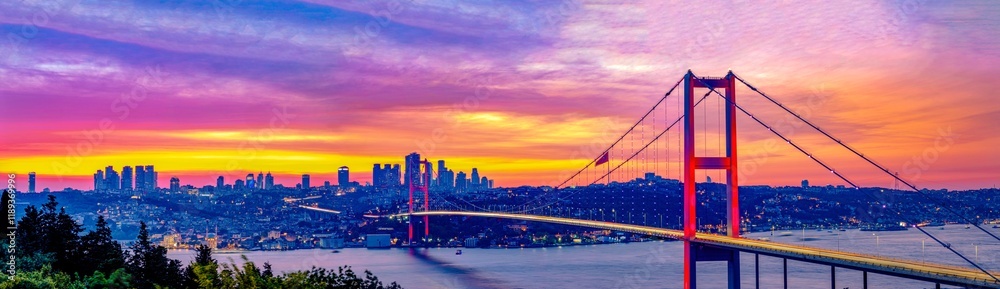 Fototapeta premium Panoramic view of Istanbul's Bosphorus Bridge at dawn.Breathtaking panoramic view of the Bosphorus Bridge in Istanbul during a vibrant sunrise or sunset. Best touristic destination Turkiye, Turkey