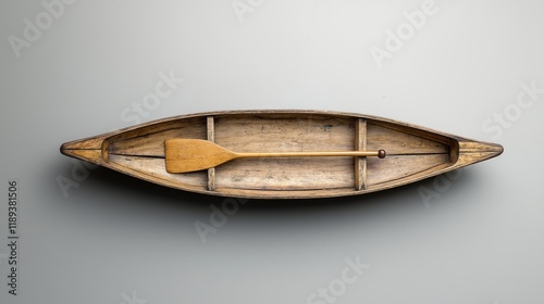 Vintage wooden canoe with paddle. Traditional watercraft crafted from wood. Simple design. Elegant antique. North American Canadian heritage. Studio shot on grey background. Detail closeup. Handmade.