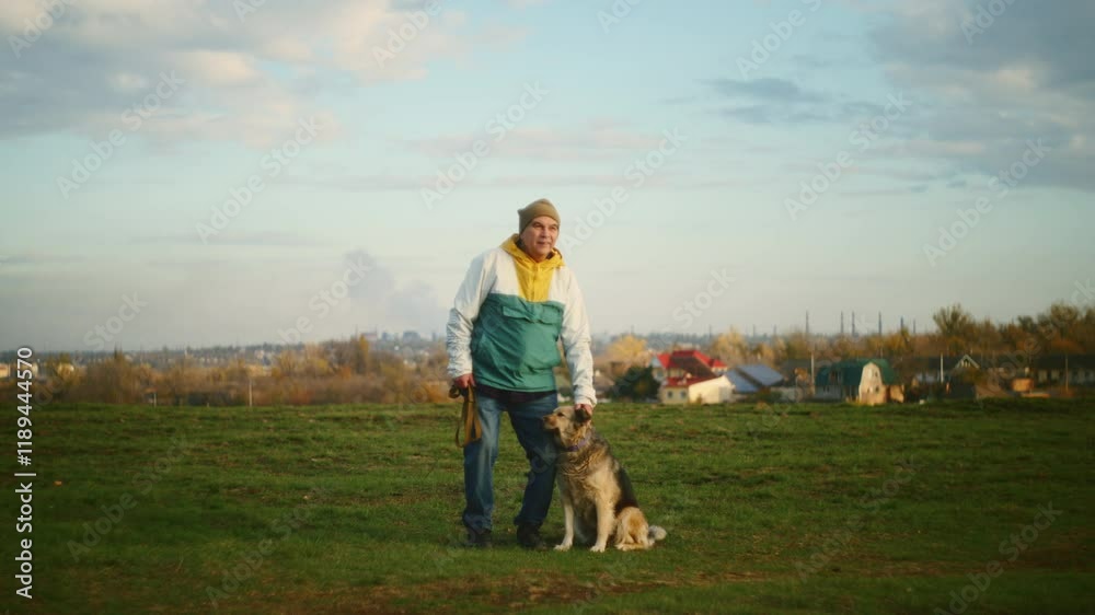 Person standing with a dog on a grassy field near a rural area. Outdoor photography with natural light. Companionship and countryside lifestyle concept. Person standing with a dog on a grassy field near a rural area. Outdoor photography with natural light. Companionship and countryside lifestyle concept.