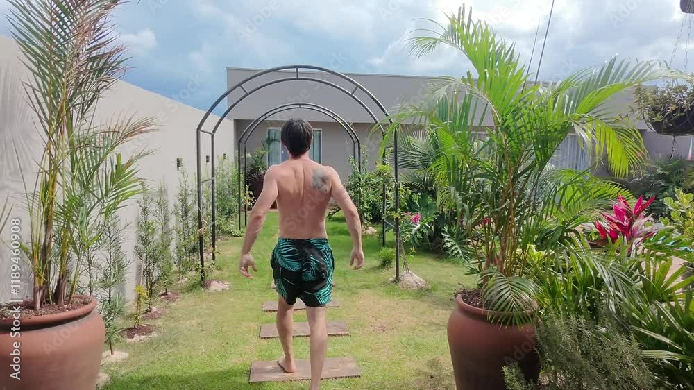 homem passeia pelo jardim com pisicna no verão 