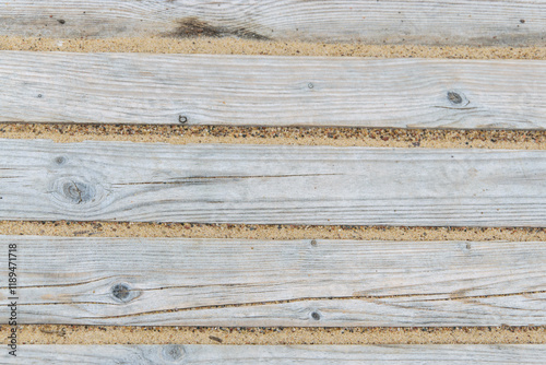 Close-up of a path made of short wooden planks on a beach.