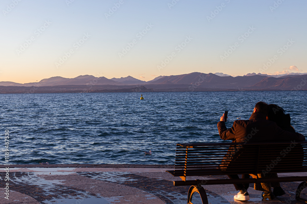 Lazise: couple takes photos at sunset on Lake Garda.