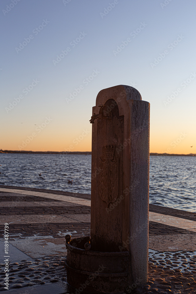 Historic fountain in Lazise at sunset. Serene atmosphere on Lake Garda.