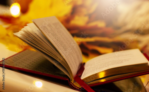 A cozy autumn scene featuring an open book with pages flipping, surrounded by golden fall leaves, warm light, and a pumpkin, creating peaceful, seasonal atmosphere perfect for relaxation and reading photo