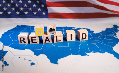 Wooden cubes composing the word rREAL ID on a map of the USA with an american flag. On May 7, 2025, U.S. travelers must be REAL ID compliant to board domestic flights and access certain federal photo