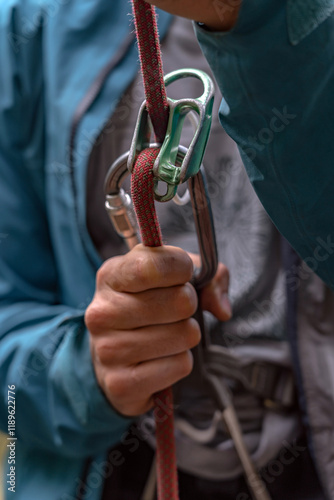 Close up of young man climber belaying leader during rock climbing outdoors, using rope, grigri, carabines and gloves. Concept of teamwork, trust, extreme sport and outdoor activity photo