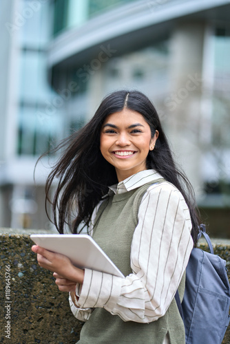 Принти на полотні Vertical portrait of happy Asian college student girl using digital tablet on street