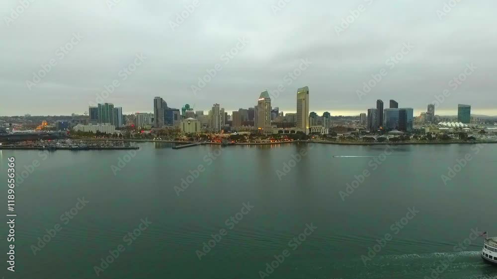Aerial Forward Time Lapse Shot Of Passenger Ship Moving On Rippled Sea By Modern Buildings In City Against Cloudy Sky - San Diego, California Aerial Forward Time Lapse Shot Of Passenger Ship Moving On Rippled Sea By Modern Buildings In City Against Cloudy Sky - San Diego, California