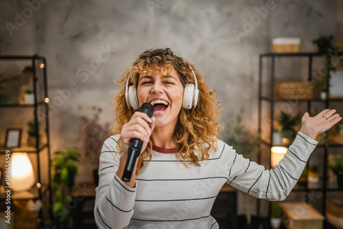 happy adult woman listen music on headphones and sing on microphone