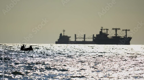 Modern pirates on an inflatable boat are about to attack a tanker or bulk carrier on the high seas. Silhouettes of sinister, unrecognizable Somali pirates.