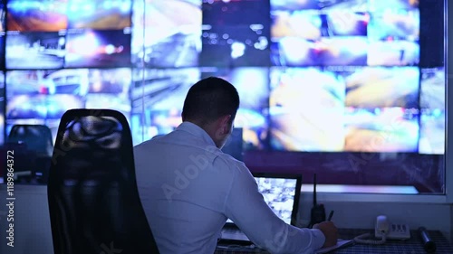 The CCTV operator is sitting and reviewing the overall situation through his laptop and recording the events.