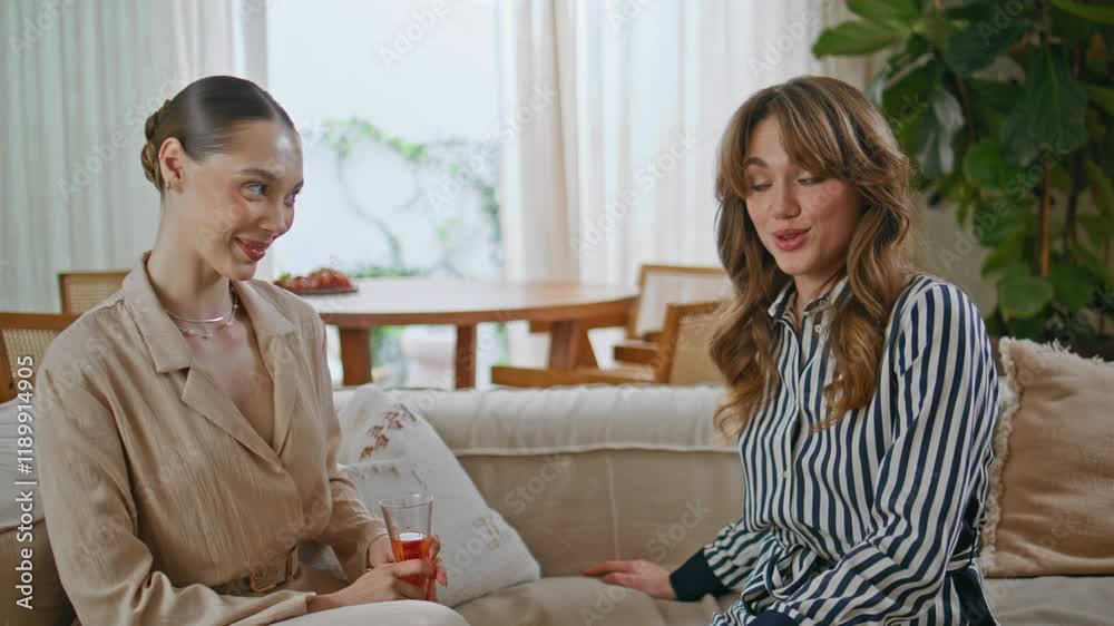 Girl friend giving gift to surprised smiling bestie on apartment couch closeup. Girl friend giving gift to surprised smiling bestie on apartment couch closeup.