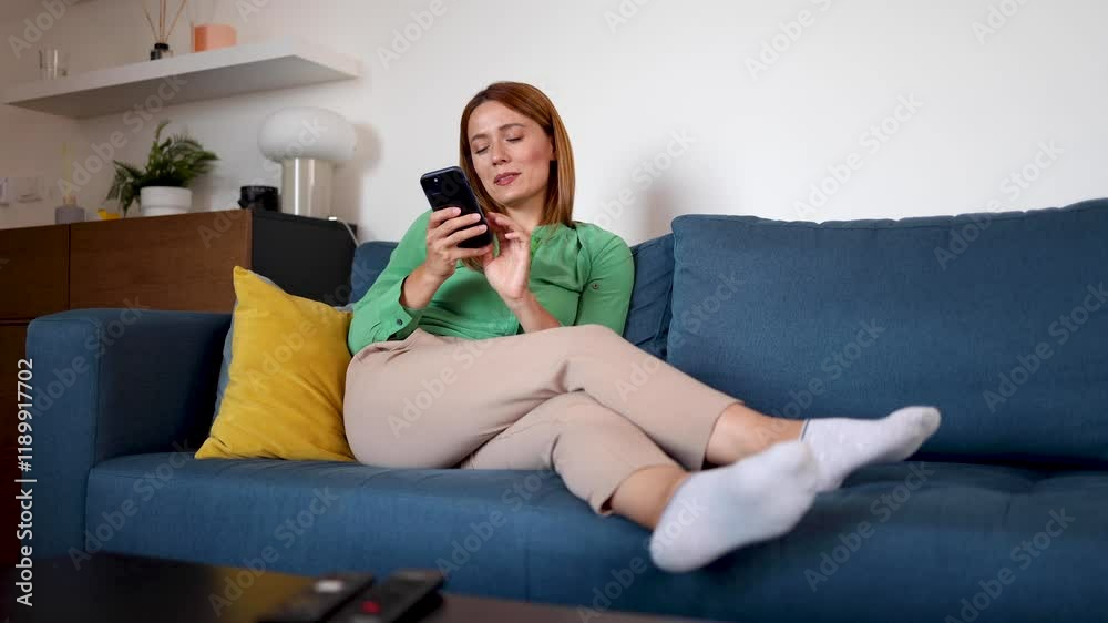 Beautiful woman relaxing at home and using her smartphone Beautiful woman relaxing at home and using her smartphone