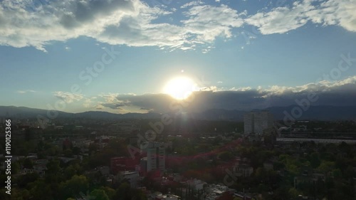 Aerial drone view of cityscaoe buildings and houses with trees and sunrise on the horizon photo