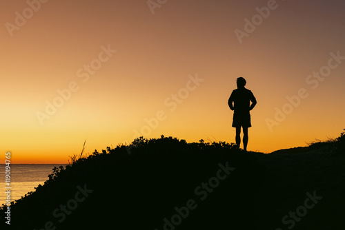 Silhouette of man standing on sand dune overlooking Beach at sunrise Hawks Nest photo