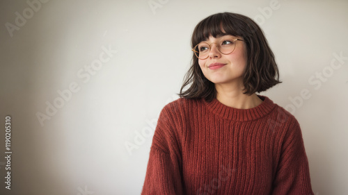 A young teenager with a cheeky smile and glasses. Looking away from the camera. The woman is cute and wearing a maroon sweater. Short brown hair. Isolated against a white background. Short brown hair.