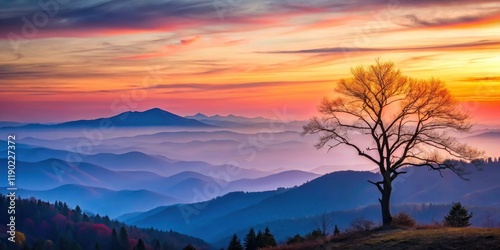 Serene Sunset Over Undulating Mountain Ranges with a Solitary Leafless Tree Silhouetted Against the Vibrant Sky