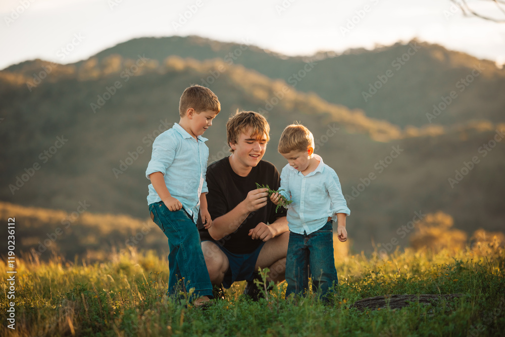 Teenager interacting with little boys on hilltop Teenager interacting with little boys on hilltop