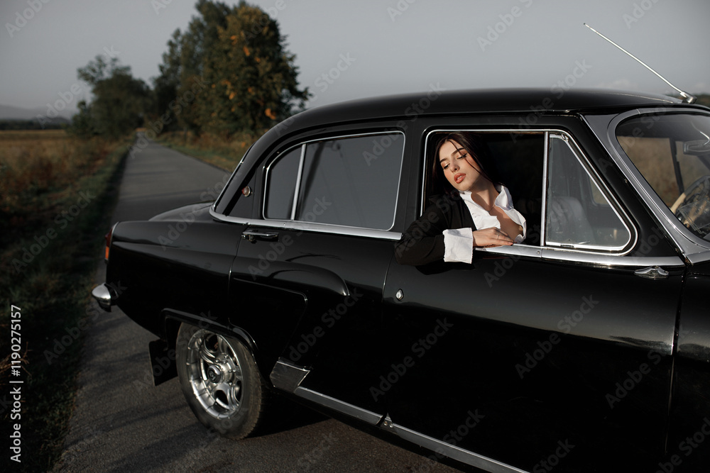 a girl looks out of the car window with her hands on the door. In the background you can see the road going into the distance and trees on both sides of the road. The sky is gray and cloudy. a girl looks out of the car window with her hands on the door. In the background you can see the road going into the distance and trees on both sides of the road. The sky is gray and cloudy.