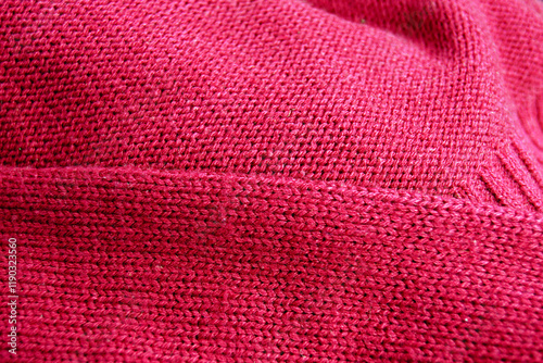 A red sweater knitted in stocking stitch: the front and back of the garment in close-up. A fabric created using the stockinette stitch technique and a fabric with a purl stitch lying next to it.