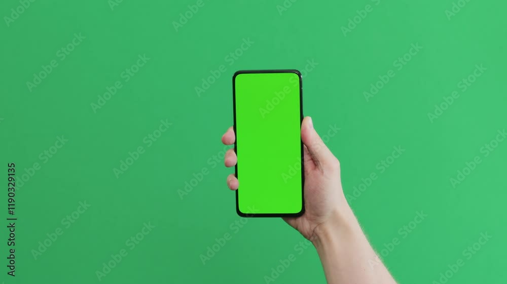 Young man hand touch smartphone with green screen on green background
