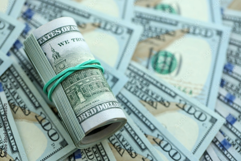 Roll of hundred dollar bills USD banknotes lies on big amount of united states money Roll of hundred dollar bills USD banknotes lies on big amount of united states money