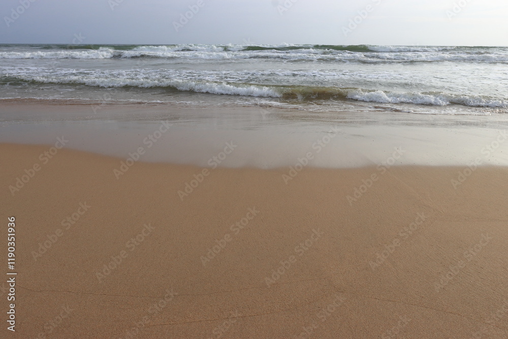 waves crashing on shore of sandy beach on a cloudy day waves crashing on shore of sandy beach on a cloudy day