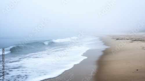 Misty shoreline with gentle waves lapping against soft sandy bea photo