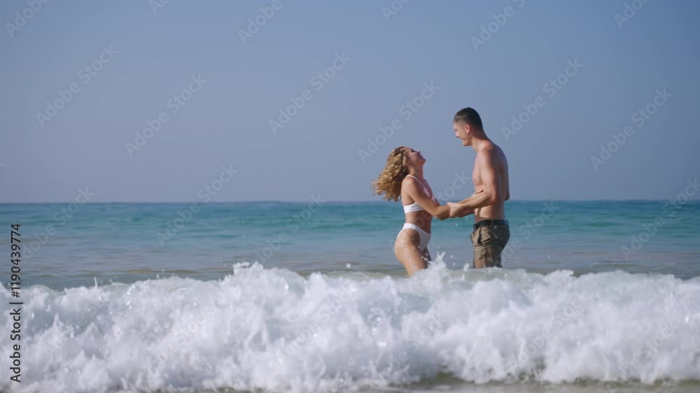 Attractive young couple having fun in sea surf waves. Fit man and woman playing in ocean near the tropical island. Girlfriend, boyfriend enjoying romantic trip in the peaceful place. Attractive young couple having fun in sea surf waves. Fit man and woman playing in ocean near the tropical island. Girlfriend, boyfriend enjoying romantic trip in the peaceful place.