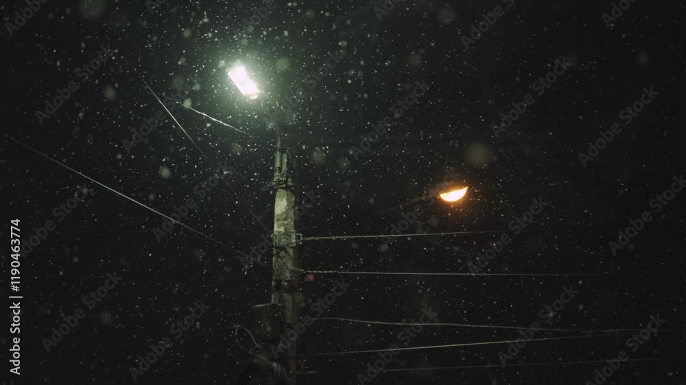 Snowfall on the background of a lantern in winter at night
