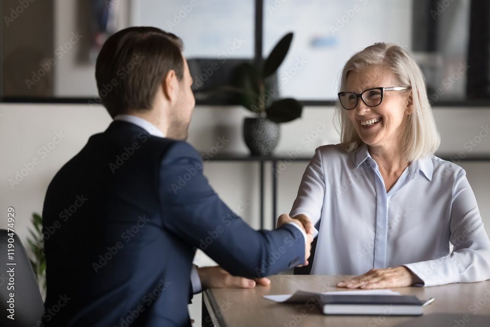 © fizkes - Two European business partners shake hands, met in office. Applicant and HR manager handshaking finish job interview successfully, candidate getting hired, expressing respect and appreciation. Trust