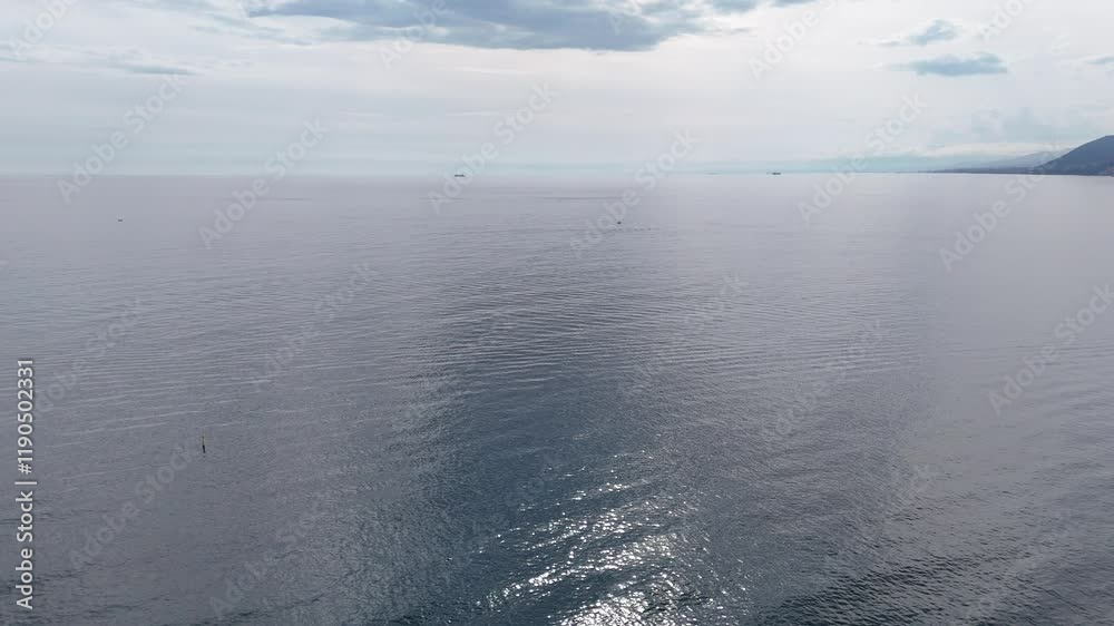 Drone shot over an open sea with sparkling water on a suny day
