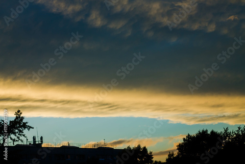 Sunset sky with clouds and silhouettes of trees on a background