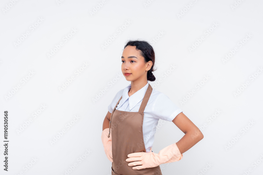 A stoic and composed young asian domestic helper, hands on hips. Isolated against a white background. A stoic and composed young asian domestic helper, hands on hips. Isolated against a white background.