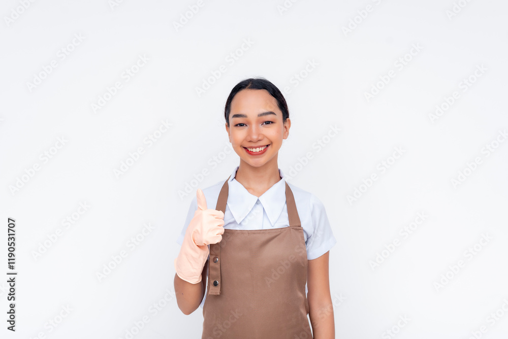 A young asian housekeeper giving her approval, making thumbs up sign. Isolated against a white background. A young asian housekeeper giving her approval, making thumbs up sign. Isolated against a white background.