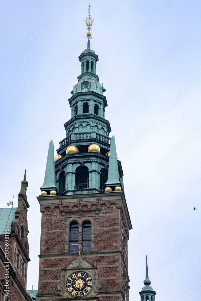 Obraz premium Tower is rectangular with a clock, observation decks and a spire with a flagpole. Freberiksborg Castle