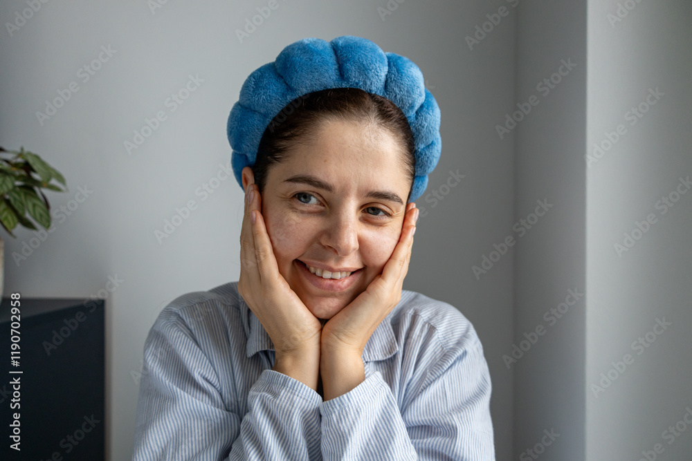 Smiling makeup-free woman with a blue headband posing joyfully in natural light Smiling makeup-free woman with a blue headband posing joyfully in natural light